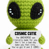 A handmade crochet alien plush toy in lime green with large black eyes and a white belly patch.