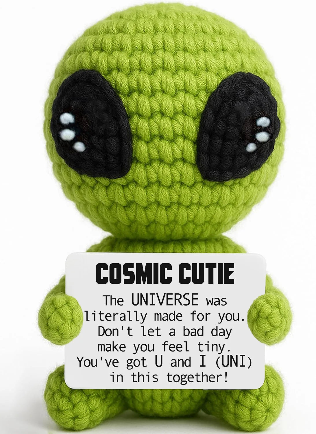 A handmade crochet alien plush toy in lime green with large black eyes and a white belly patch.