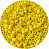A close-up view of small yellow pony beads scattered on a white background.