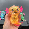 A hand holds a squishy axolotl stress relief toy with bright orange and pink translucent body and fins.