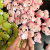 A close-up of many handmade crochet dinosaur keychains in pink and green colors.