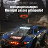 A blue off-road monster truck is driving through a dusty environment with bright LED headlights at night.