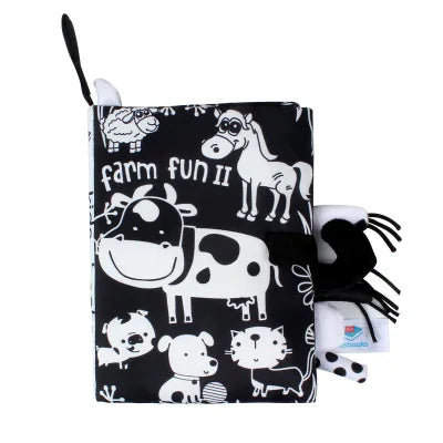 A black cloth book featuring farm animal illustrations like a cow and horse for sensory play.