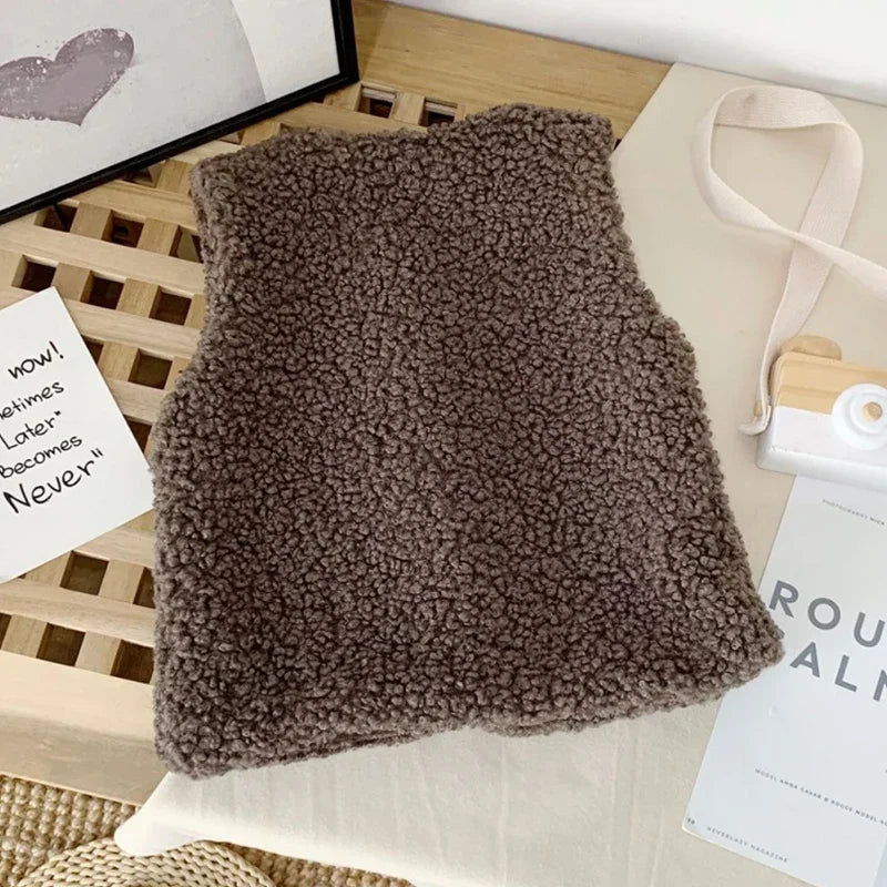 A dark brown, fluffy lamb wool vest is displayed on a light surface.