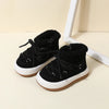 A pair of black baby winter snow boots with plush lining and anti-slip rubber soles resting on a light surface.