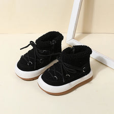 A pair of black baby winter snow boots with plush lining and anti-slip rubber soles resting on a light surface.