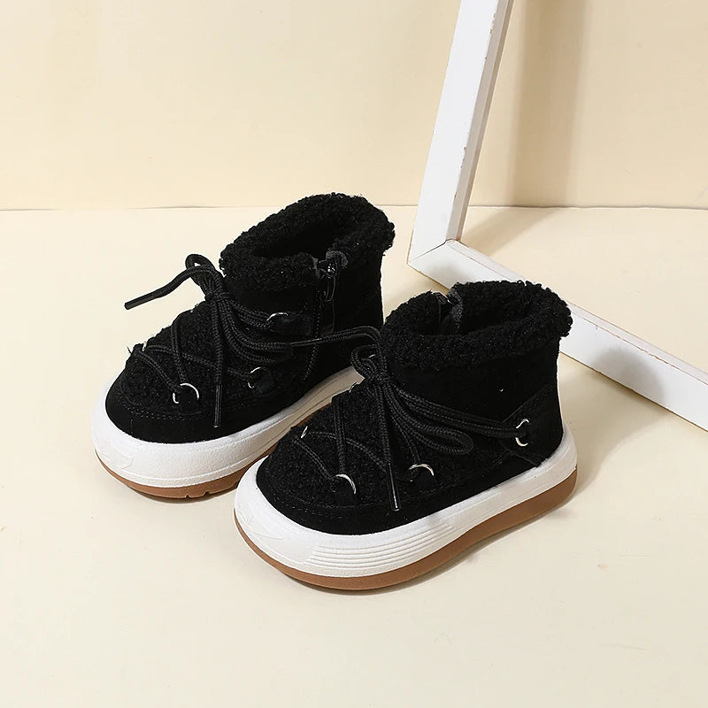A pair of black baby winter snow boots with plush lining and anti-slip rubber soles resting on a light surface.