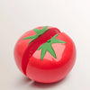A bright red plastic tomato with a green stem, shown for 360 degree fine polishing.
