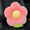 A pink plush lumbar support pillow with a yellow center and green base resting on a black car seat.