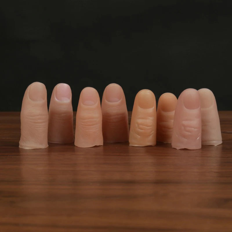 A row of realistic silicone fake thumb tips or fingers arranged horizontally on a wooden surface.