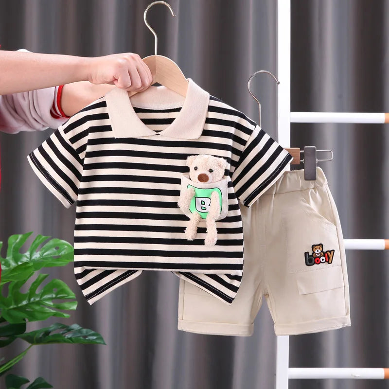 A striped kids outfit set featuring a black and white shirt and beige shorts hanging on a wooden hanger.