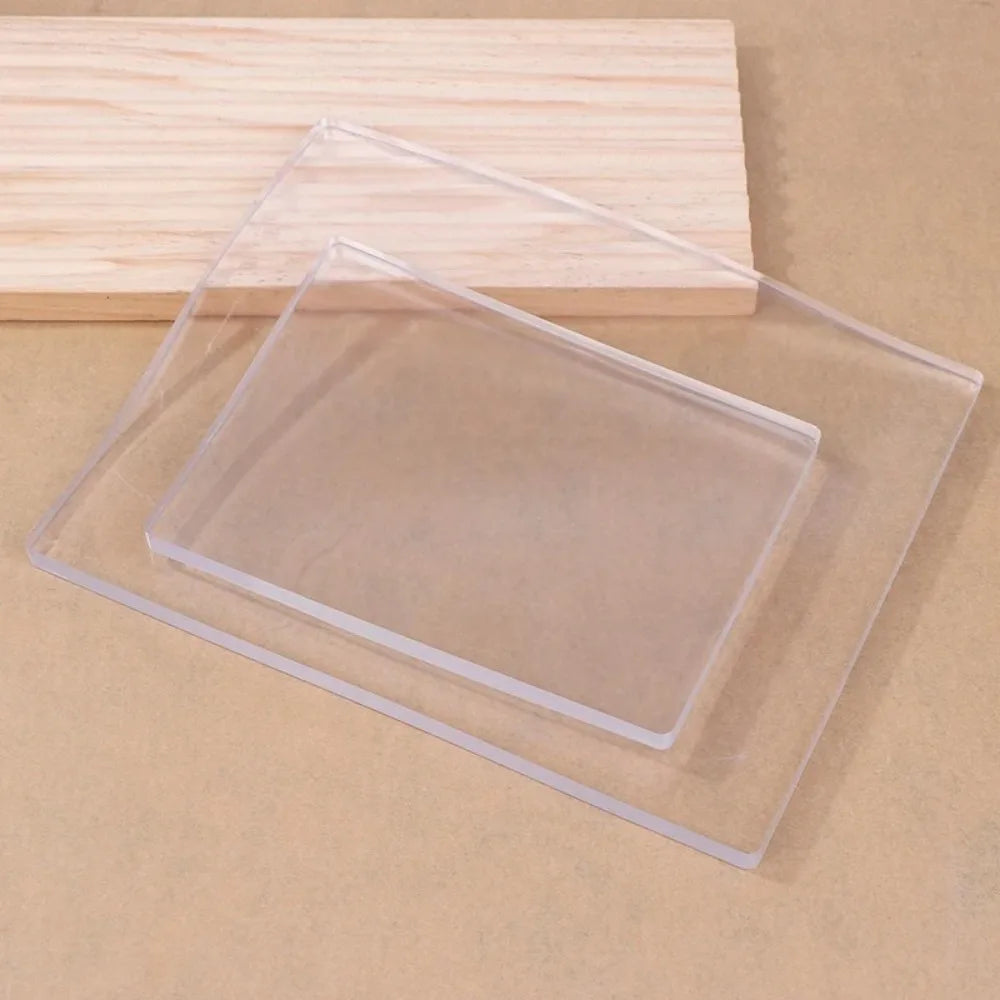 Clear silicone gel printing plates stacked on a light wooden board.