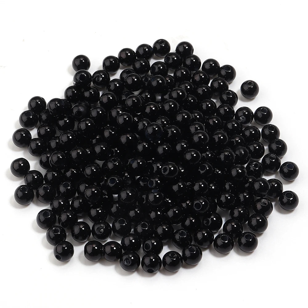 A pile of small, round, black imitation pearl beads for jewelry making.