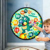 A young boy is holding a large cloth dart board set with sticky balls featuring dinosaur and number targets.
