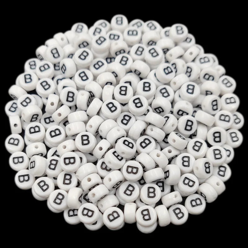 A pile of small white acrylic alphabet letter beads for jewelry making