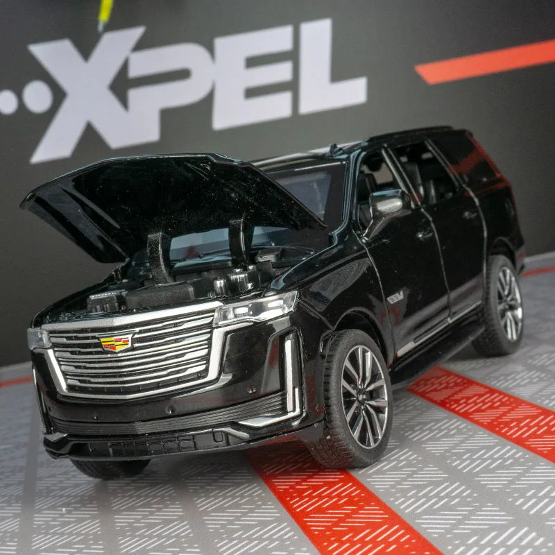 A black 1:32 diecast Cadillac Escalade pull-back model car with the hood open, displayed on a gray surface.