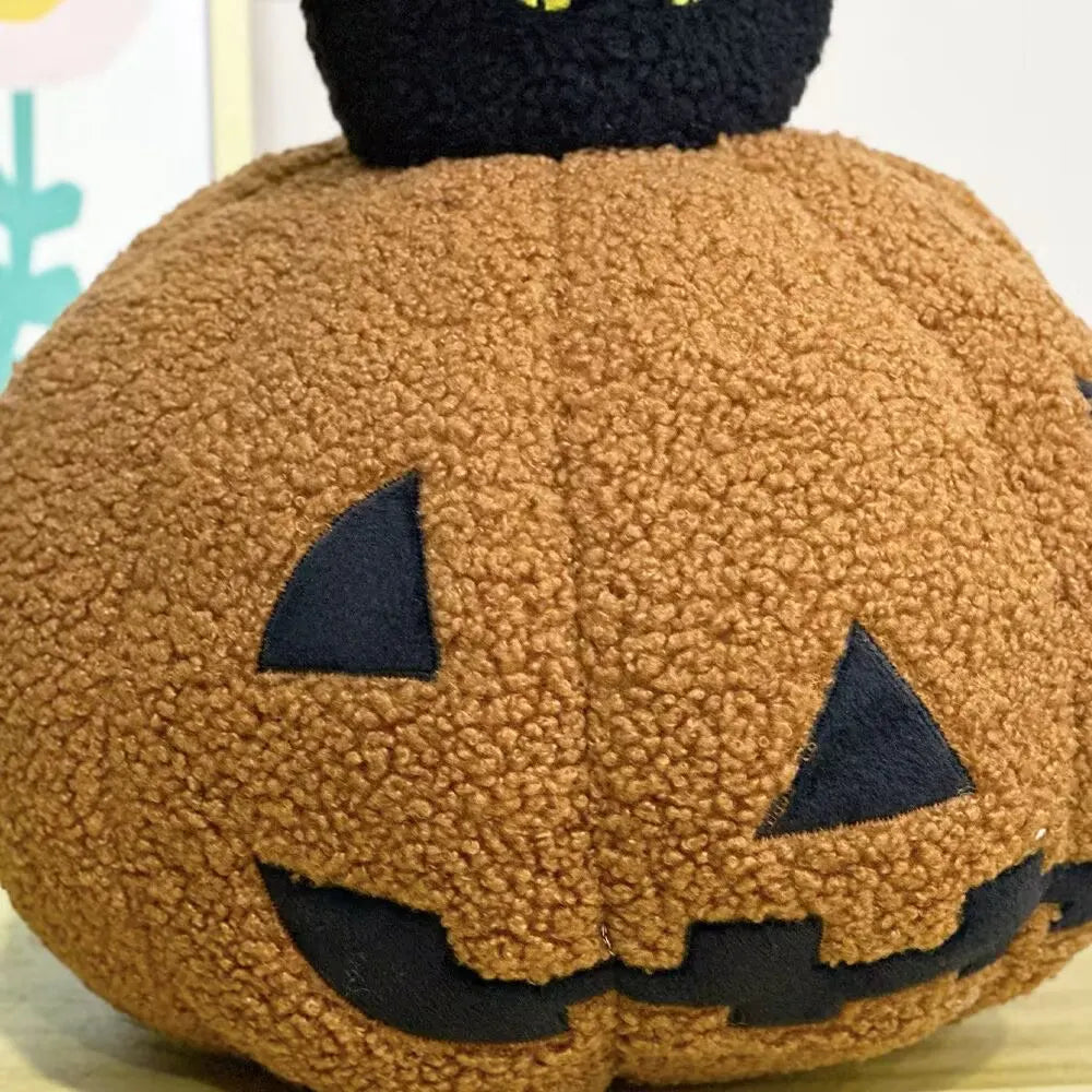 A fluffy brown pumpkin plush toy with black cat features and a black nose.