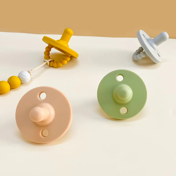 A collection of yellow and white silicone baby pacifiers and soothers on a white surface.