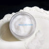 A clear jar filled with white adhesive flocking powder resting on a white ceramic dish.