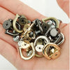 A collection of D-shaped metal bag handles and hardware including rings, clasps, and screws held in a person's hand.