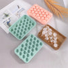 A collection of silicone grape cluster molds in pink and green are displayed on a white surface.