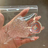 A hand holds a clear plastic pouch containing a pink glittery strawberry squeeze fidget toy.
