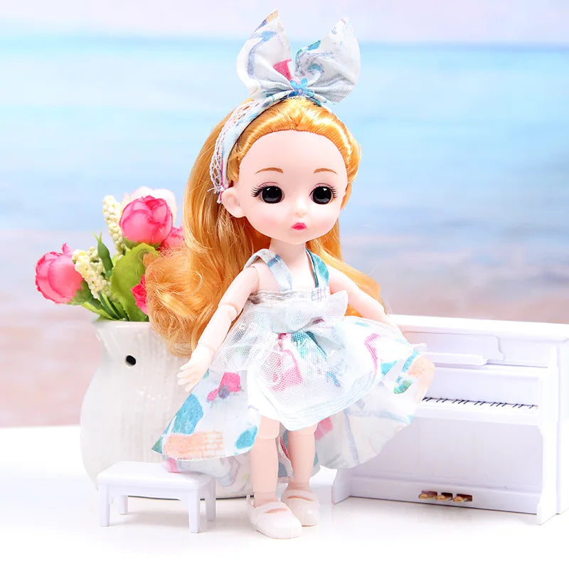 An orange-haired doll with a bow is shown wearing a light blue dress next to a white piano on a white surface.
