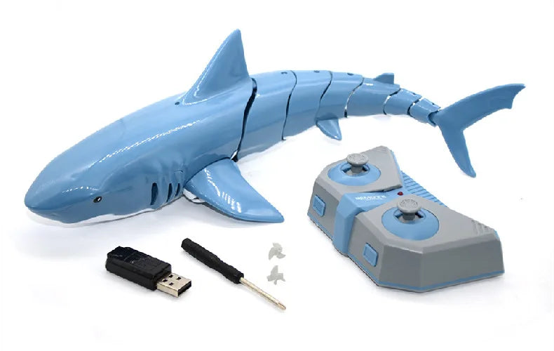 A blue shark toy model with a light and water spray attachment, along with its remote control and accessories.