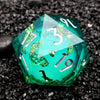 A vibrant green resin D20 die with silver numbers and iridescent liquid swirls resting on black gravel.