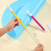A hand holds a yellow slide whistle toy, demonstrating its use against a blue plastic slide.