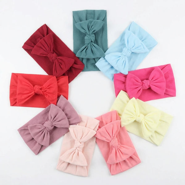 A collection of pink, red, and blue soft elastic headbands tied in bows arranged in a circle.