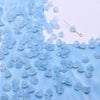 A scattering of small, light blue glass beads resembling lily of the valley flowers on a white background.