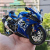 A blue Suzuki ECSTAR RSX diecast motorcycle model is held in a hand.