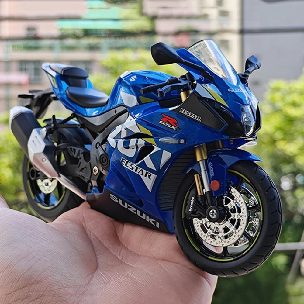 A blue Suzuki ECSTAR RSX diecast motorcycle model is held in a hand.