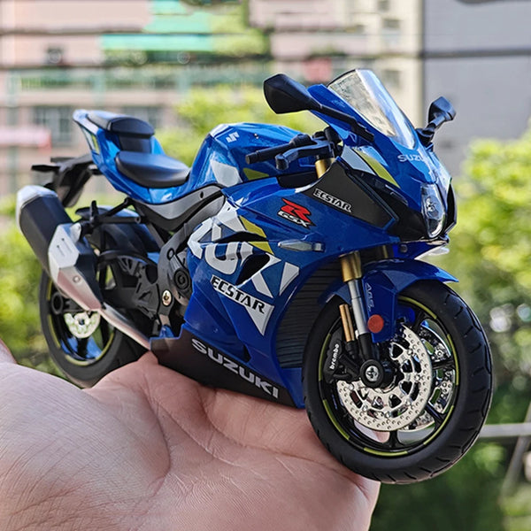 En blå Suzuki ECSTAR RSX diecast motorcykelmodel holdes i en hånd.