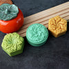 A collection of flexible silicone flower molds in orange, yellow, and green resting on a wooden board.
