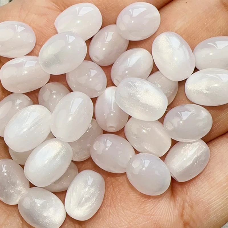 A pile of ten translucent white and pink resin starry sky cat's eye beads for jewelry making