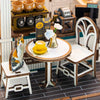 A detailed miniature coffee shop scene featuring a wooden dollhouse kit, a small yellow cup, and a cat figurine.