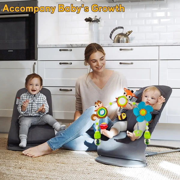 A mother is holding a baby in an adjustable musical activity arch while sitting on the floor.