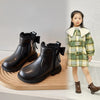 A girl models black ankle boots with bow-knot detail and a side zipper, standing next to the footwear.