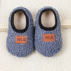 Pair of gray plush baby slippers with black lining and wooden anti-slip soles