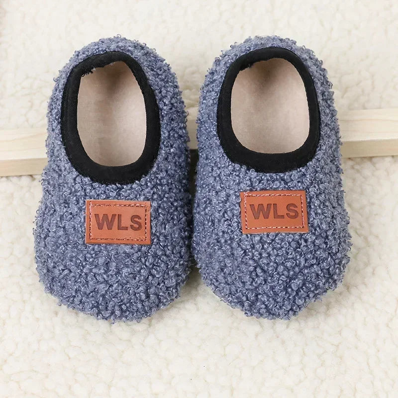 Pair of gray plush baby slippers with black lining and wooden anti-slip soles