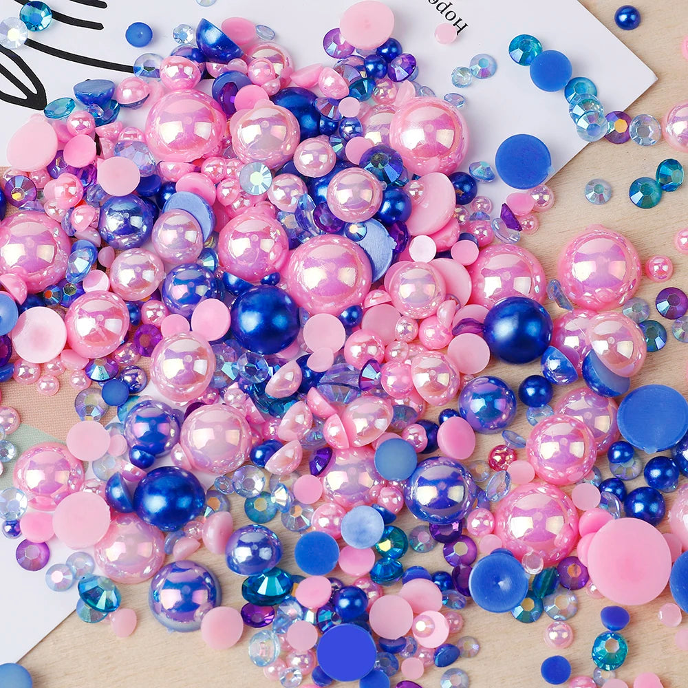 A colorful mix of pink, purple, and blue resin rhinestone pearls with an AB finish scattered on a light surface.