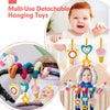 Un bébé tient un ensemble de jouets suspendus détachables et colorés, comprenant des maracas et des miroirs.