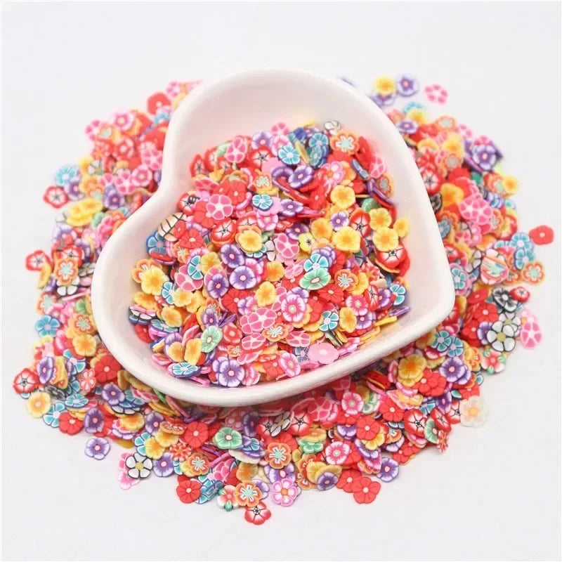 A white dish filled with colorful polymer clay sprinkles for slime and craft decor, scattered on a white background.