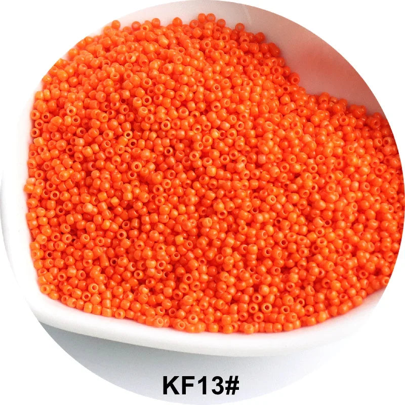 A pile of bright orange 1.5mm solid glass seed beads for jewelry and craft.