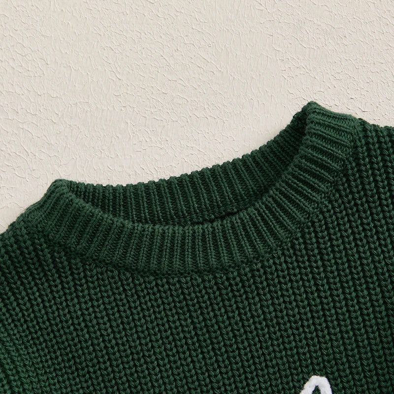 A close-up of a dark green knit sweater with white embroidery detail on the chest.