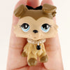 A small, light brown miniature pet animal figure with large blue eyes and a black collar is held in a person's hand.