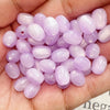 A handful of iridescent lavender and pink resin star-like cat's eye beads for jewelry making