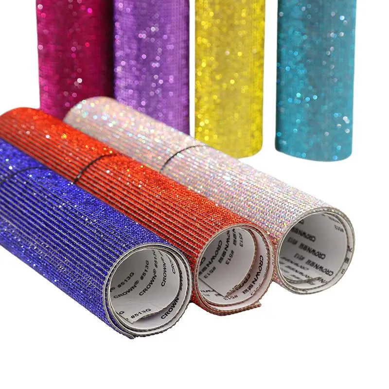A collection of colorful sparkling rhinestone adhesive tape rolls in various shades including purple, yellow, pink, and blue.